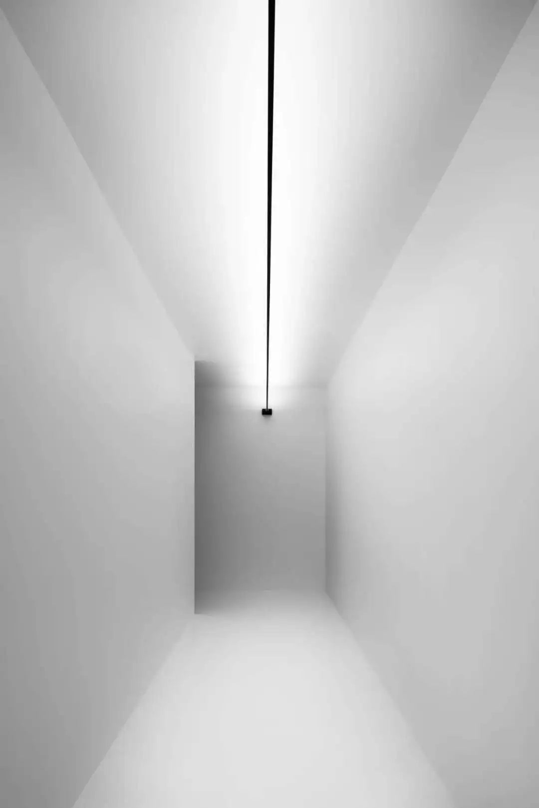 A Stream of Light Suspension Light in vertical configuration delivering dramatic layered lighting within a pristine white corridor, Domus Collective contemporary suspended lights.