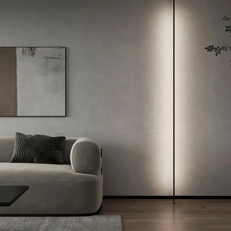 A Stream of Light Suspension Light mounted vertically in a sophisticated grey living room creating wellness-focused ambient warmth, Domus Collective minimalist lighting.