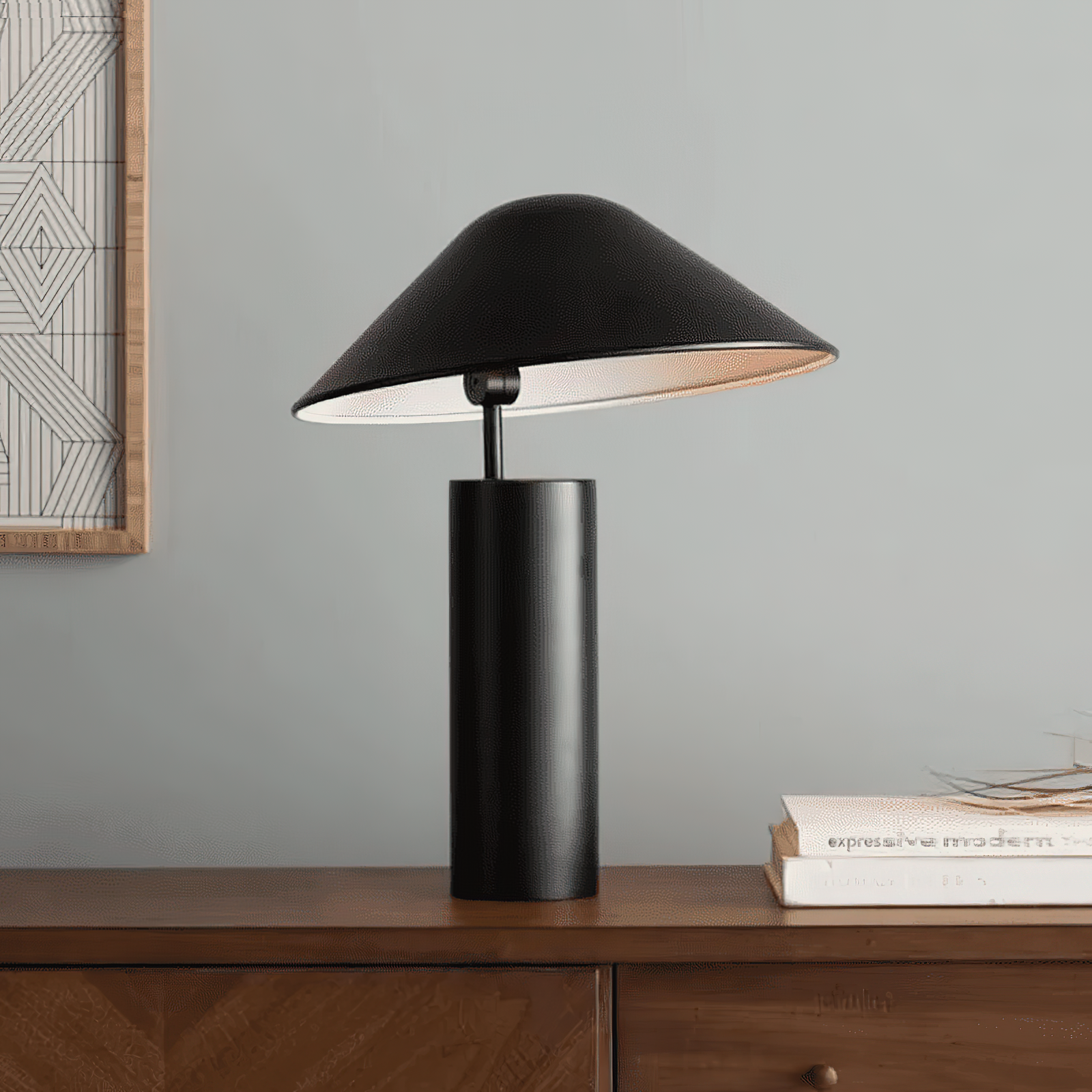 Asymetra table lamp,by domus collective with textured matte black aluminum body, tilted mushroom shade revealing white interior, and cylindrical base positioned on a mid-century modern credenza.