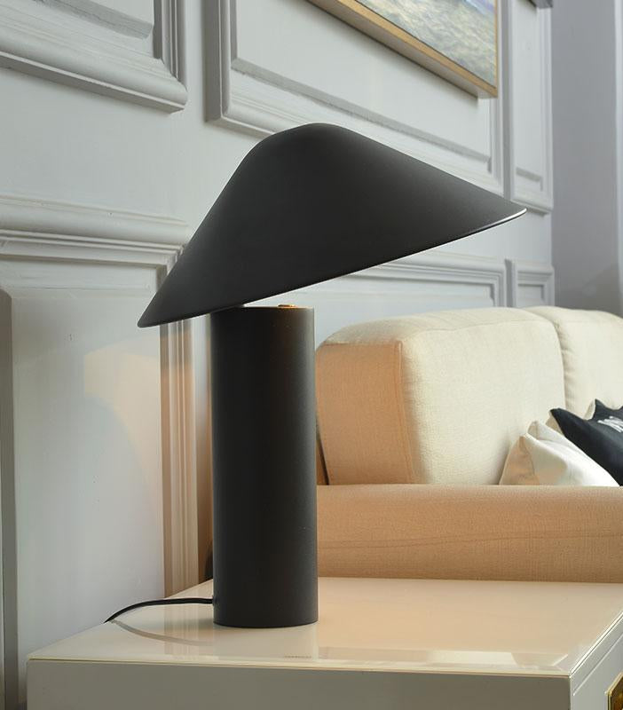 Asymetra Table Lamp in charcoal matte finish with dramatically angled conical shade, bringing sculptural presence to a classic Parisian interior with paneled walls, by Domus Collective.