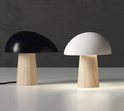 Two mushroom-shaped table lamps, one black and one white, on a dark background.