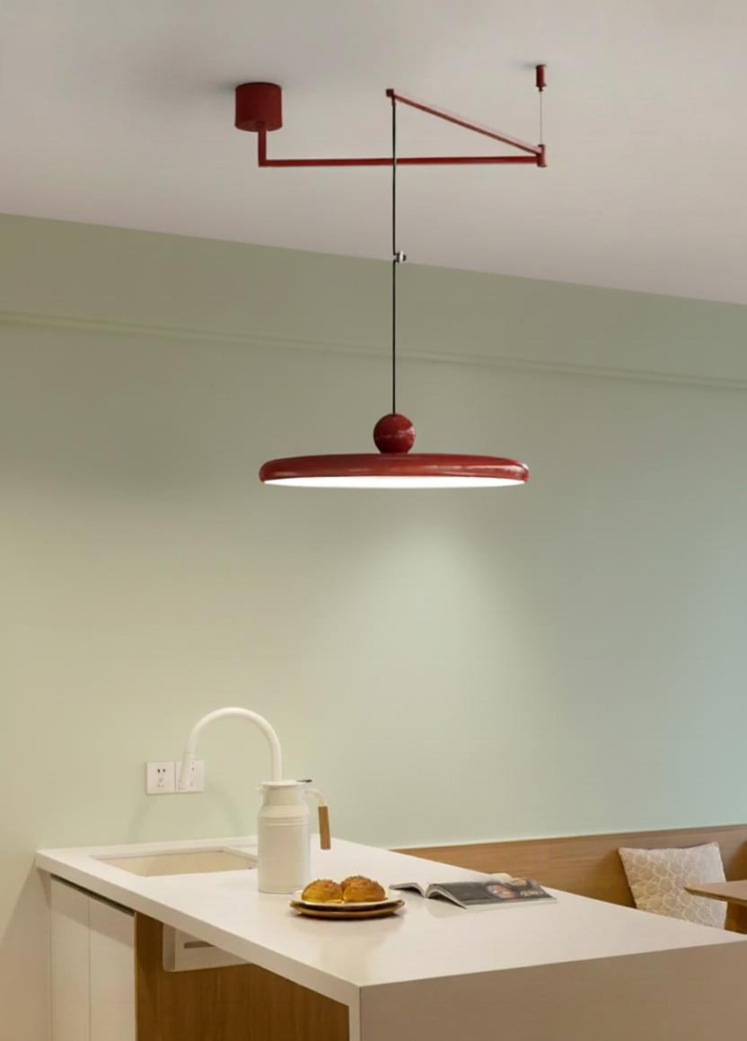 Cirra Pendant Light in glossy red with wide disc shade and decorative sphere accent, suspended from a swing arm bracket above a contemporary kitchen island by Domus Collective.
