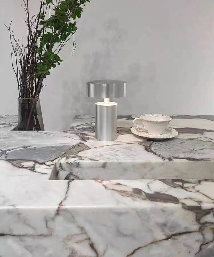 Minimalist Cologne Halo Night Portable Light in silver iron finish on a dramatic veined marble surface, its clean geometric form complementing luxurious stone textures for refined interiors.