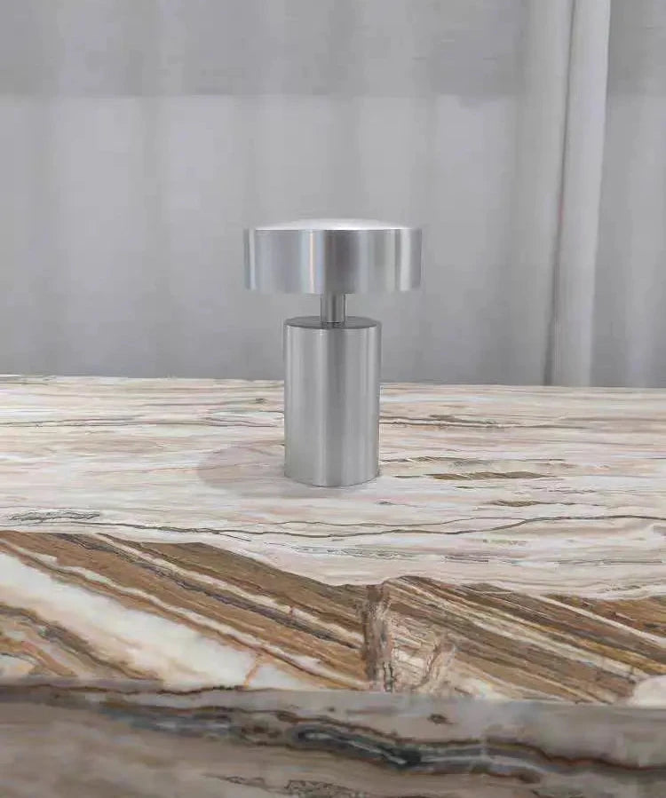 Brushed silver Cologne Halo Night Portable Light with cylindrical base and disc shade positioned on richly veined onyx marble, delivering quiet balance and understated sophistication for Australian homes, by Domus Collective.