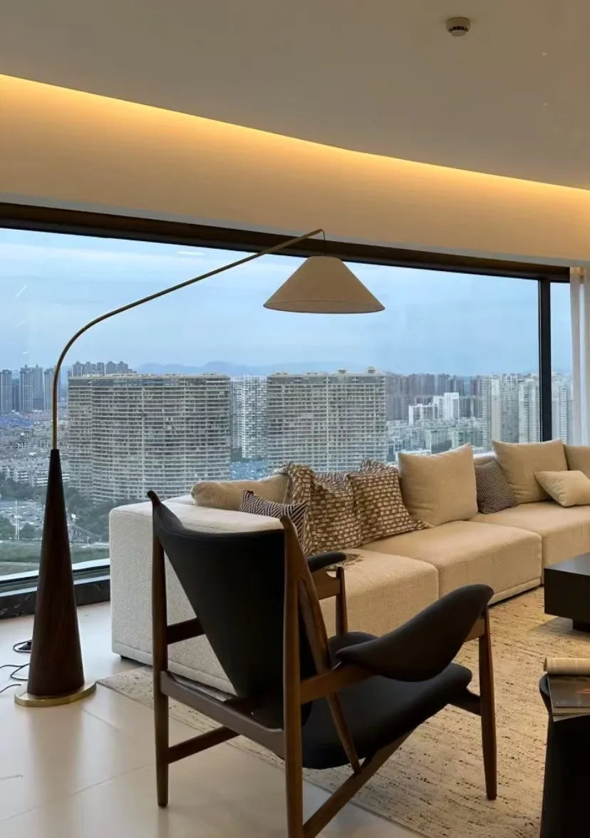 Domus Collective Driftwood Reel Floor Lamp with dark wood tapered base and cream shade positioned in high-rise apartment with panoramic views, timeless organic design delivering soft illumination for elevated living.
