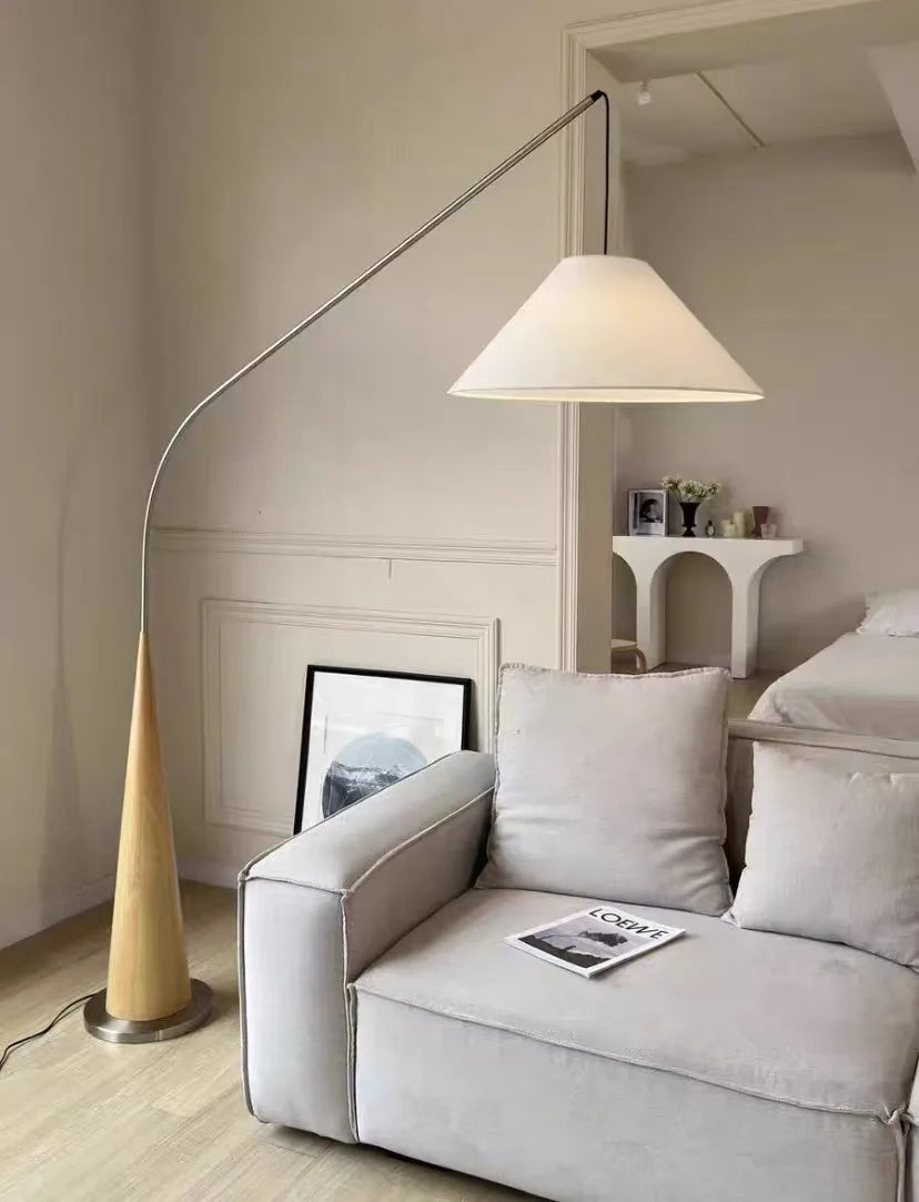 Elegant Driftwood Reel Floor Lamp featuring blonde timber cone base and chrome curved arm with ivory linen shade beside linen sofa,a Domus Collective where natural materials meet refined Scandinavian aesthetics.