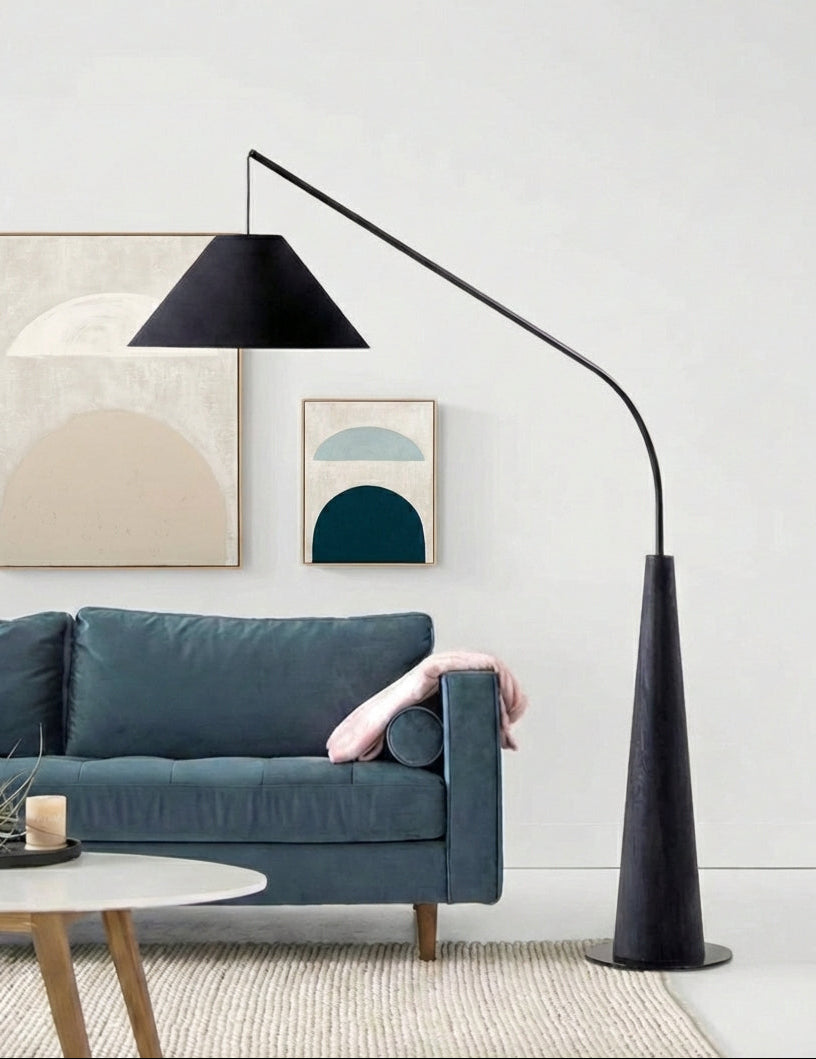 Architectural Driftwood Reel Floor Lamp in black with dark conical base beside teal velvet sofa and abstract artwork,a Domus Collective statement piece blending organic form with modern sophistication.