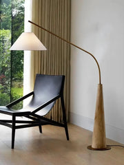 Driftwood Reel Floor Lamp by Domus Collective with sculptural blonde wood conical base and arched brass arm supporting linen cone shade ,organic floor lighting bringing natural warmth to contemporary Australian interiors.
