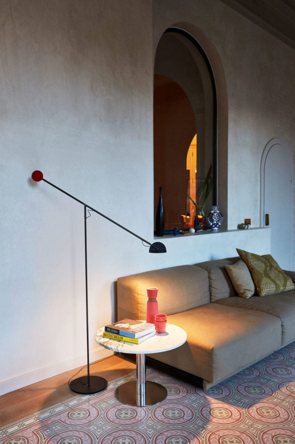 Positioned beside a quilted gray sofa, this all-black Dynamic Equilibrium Floor Lamp casts warm directional light while its minimalist balance arm creates a striking silhouette against contemporary gallery walls, by Domus Collective.
