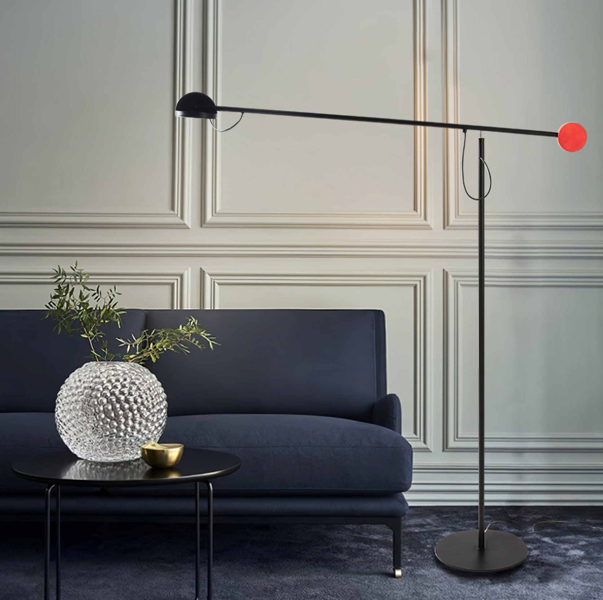 Full view of the Dynamic Equilibrium Floor Lamp showcasing its architectural balance beam design with matte black dome shade and contrasting red spherical counterweight on a slim pedestal base, by Domus Collective.