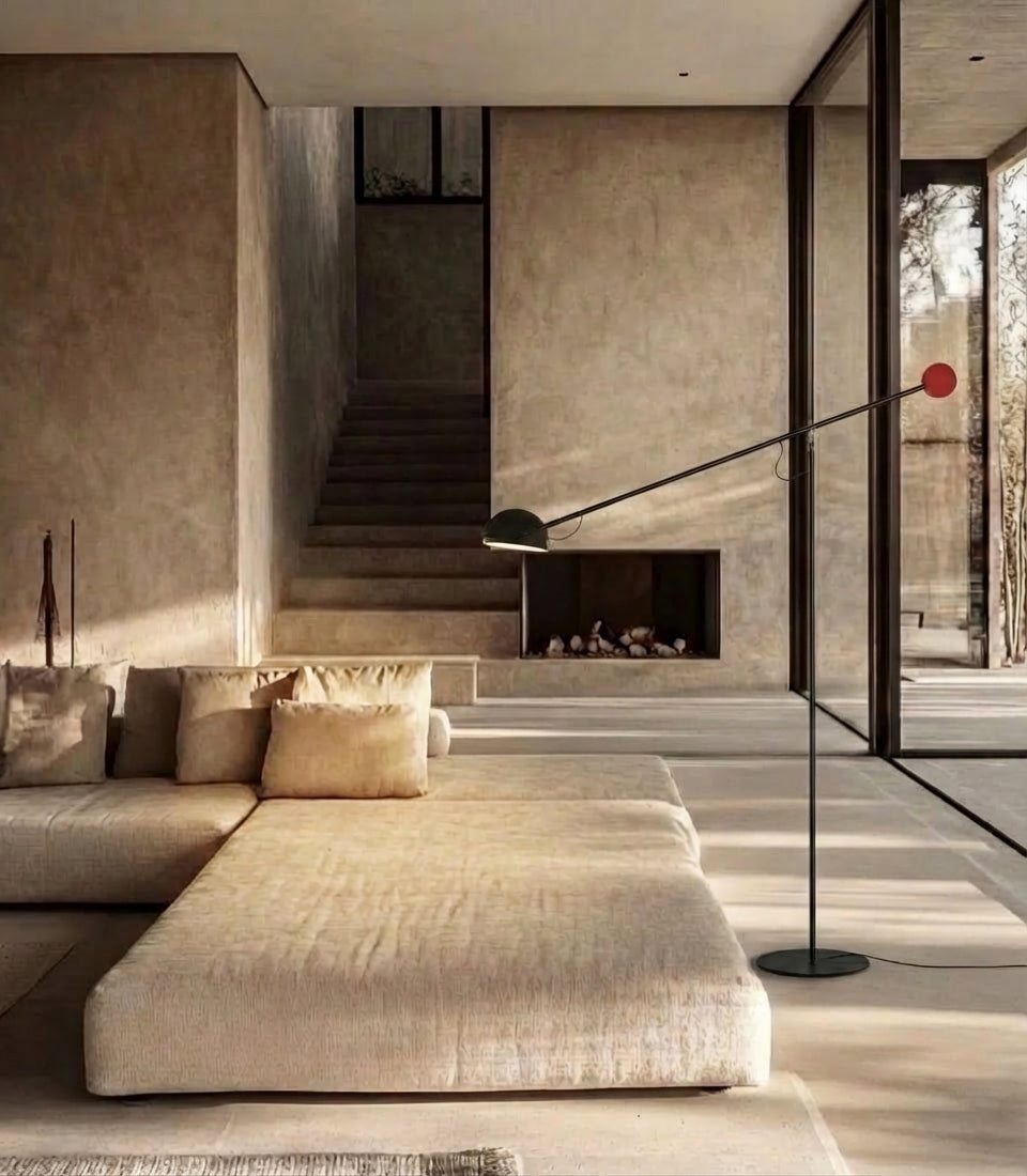 The Dynamic Equilibrium Floor Lamp in matte black with a bold red counterweight sphere stands beside a navy velvet sofa, its balanced cantilevered arm adding sculptural sophistication to elegant Parisian-style interiors, by Domus Collective.