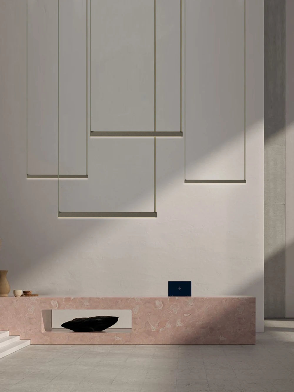 Multiple Grey Bar,EmDash Suspension Lights dropping at different heights, their clean linear steel forms creating a stunning layered lighting display above a pink stone console - a timeless, architectural pendant light collection by Domus Collective.