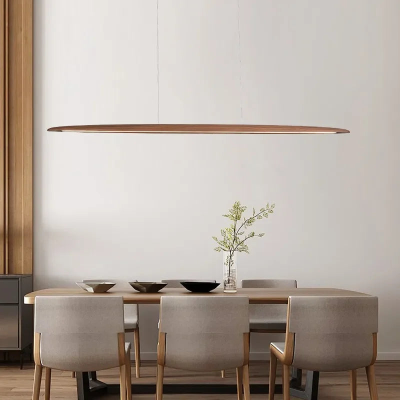 Walnut-toned Float Board Pendant Lamp suspended above contemporary dining table, refined elongated wood fixture with integrated LED for elegant minimalist interiors, by Domus Collective.