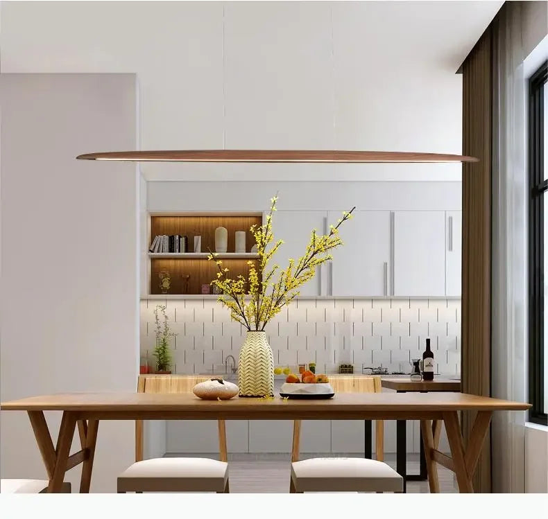 Artisan Float Board Pendant Lamp in rich wood grain finish hovering over kitchen dining area, curated linear pendant blending coastal ease with modern sophistication, by Domus Collective.