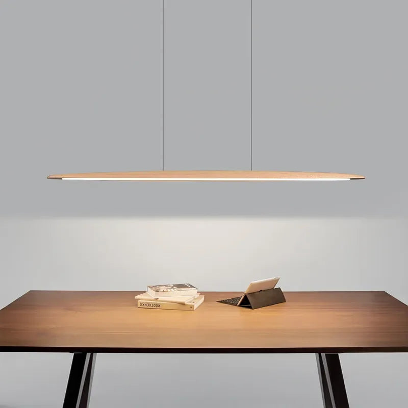 Float Board Pendant Lamp in light bamboo finish illuminating a modern workspace, sleek surfboard-shaped LED fixture crafted for focused, calming home office ambiance, by Domus Collective.
