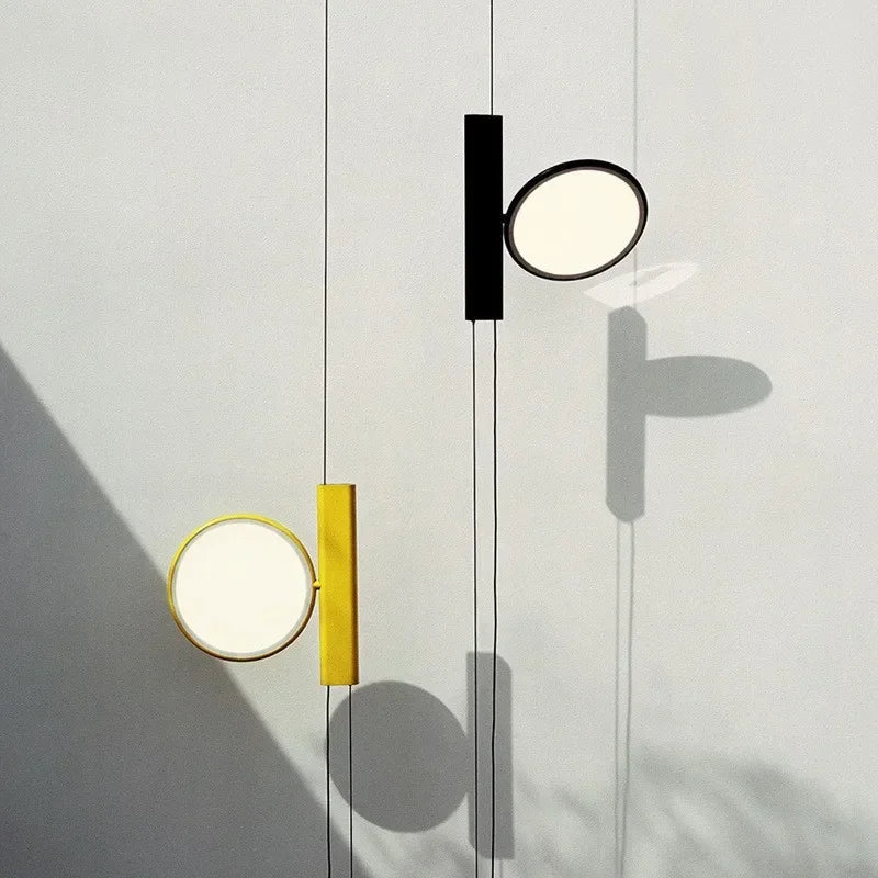 Minimalist suspended Suspension Lights in matte black and sunny yellow casting soft ambient glow with dramatic wall shadows, artisan crafted lighting by Domus Collective.