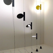 Sculptural  Suspension Lights with circular disc shades in black and yellow finishes suspended at varying heights, modern designer lighting by Domus Collective.
