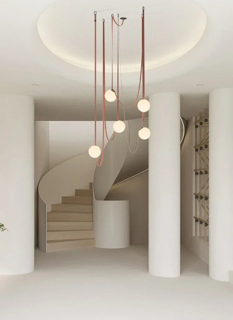 Artisan-crafted Floating Moons Pendant Light with five luminous globes on cognac leather straps, modern statement chandelier for grand stairwell entryways, by Domus Collective.