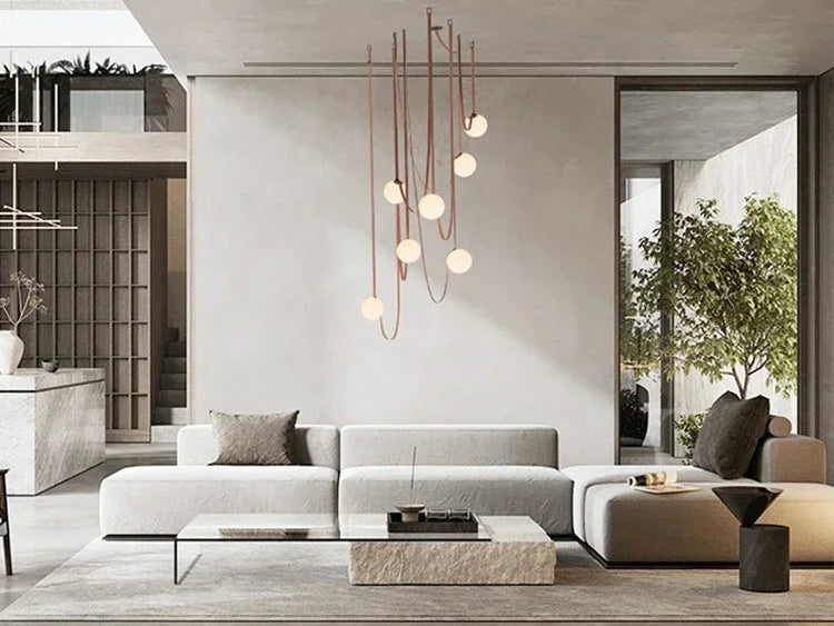 Floating Moons Pendant Light with cascading frosted orbs and leather cord detail, handcrafted chandelier adding dreamy ambiance to luxe contemporary living rooms, by Domus Collective.
