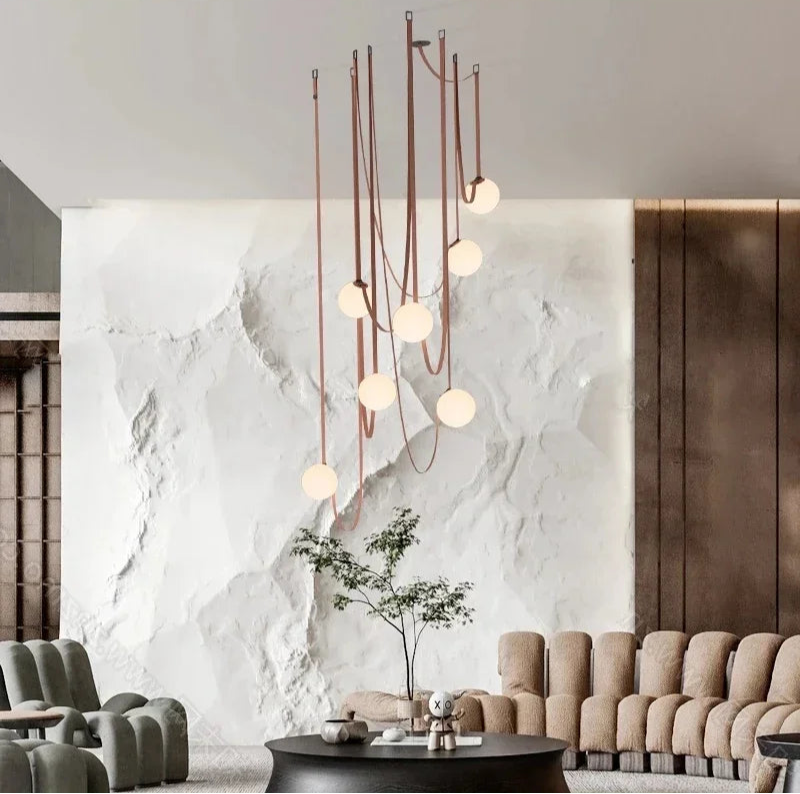 Dramatic Floating Moons Pendant Light installation with multiple glowing spheres against textured stone wall, artisan lighting as sculptural centerpiece for designer lounges, by Domus Collective.