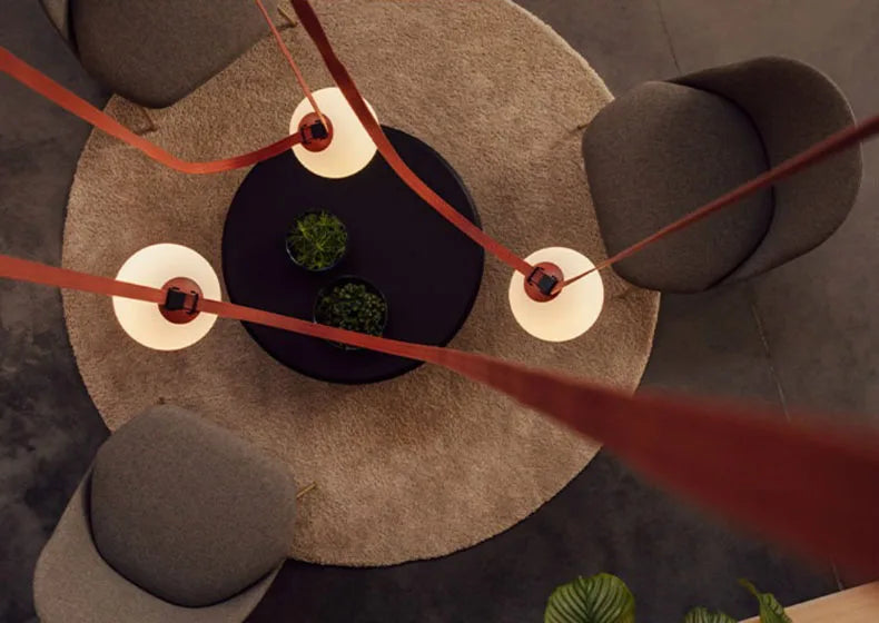 Overhead view of Floating Moons Pendant Light with terracotta leather cords weaving between illuminated glass orbs, modern pendant creating constellation-like patterns above seating areas, by Domus Collective.