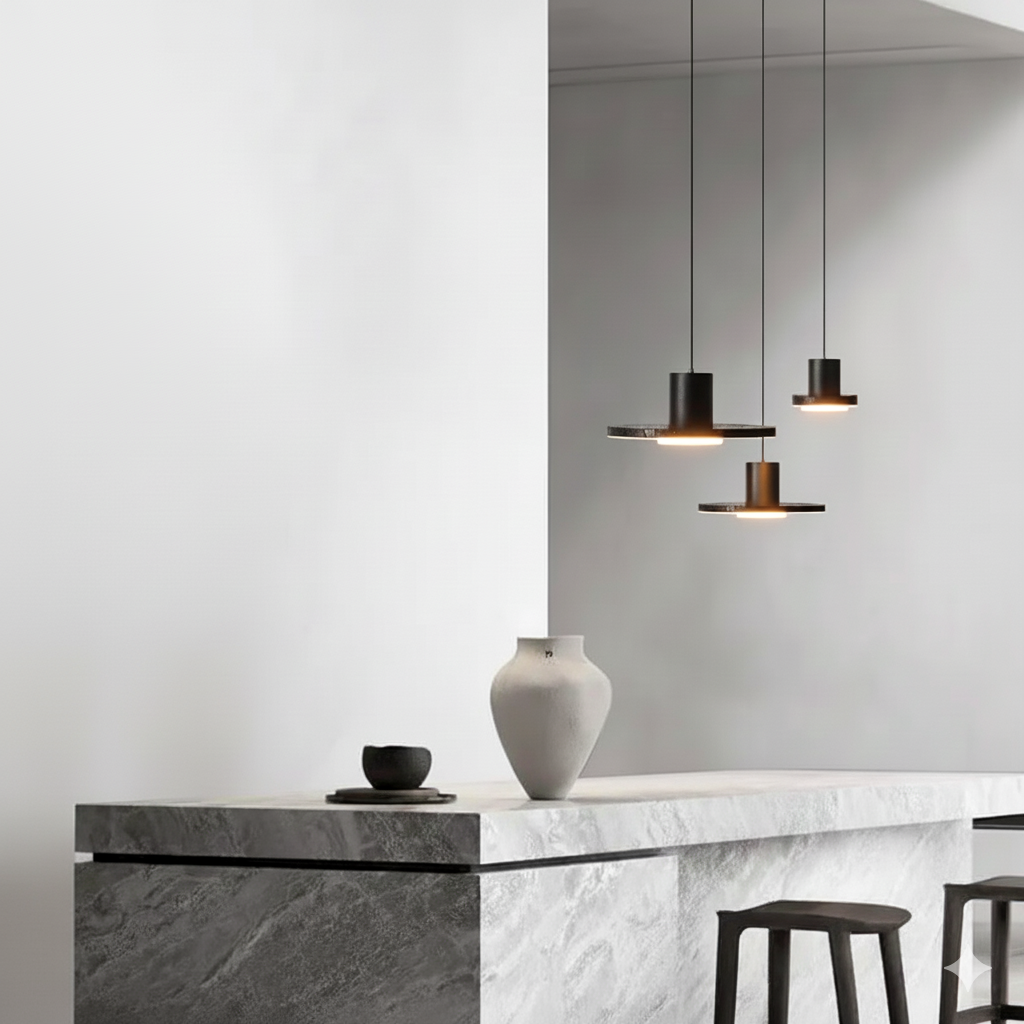 Galaxia Suspension Lights cluster featuring volcanic stone disc shades with matte black metal cylinders, suspended at staggered heights above a sculptural marble kitchen island by Domus Collective.