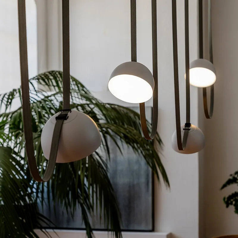 Matte white Hemisphere Suspension Light cluster with olive leather straps, handcrafted dome pendants casting soft focused glow for inviting living areas, by Domus Collective.