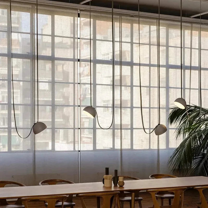Industrial-chic Hemisphere Suspension Light arrangement with four gray dome shades over long dining table, artisan lighting designed for loft-style gathering spaces, by Domus Collective.