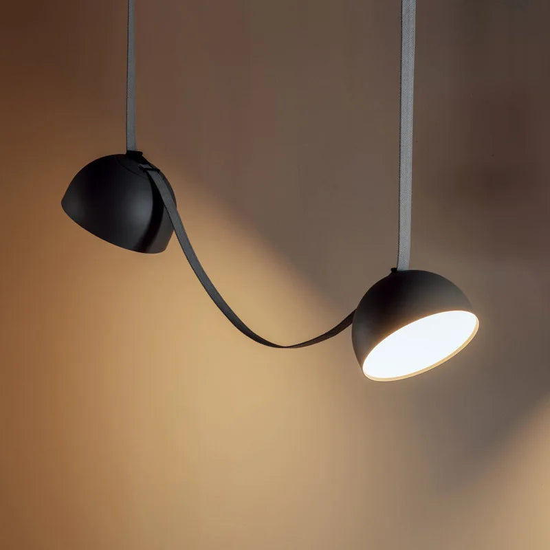 Dual matte black Hemisphere Suspension Light connected by curved leather cord, sculptural pendant design adding bold character to warm contemporary interiors, by Domus Collective.