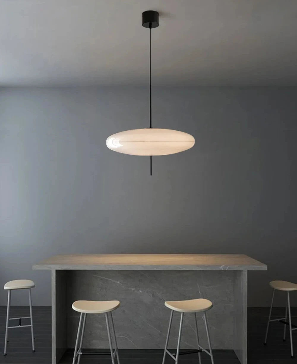 Modern Domus collective pendant light called Hovering Cloud Pendant Lighth in white hanging above a dining table with stools in a minimalistic setting.