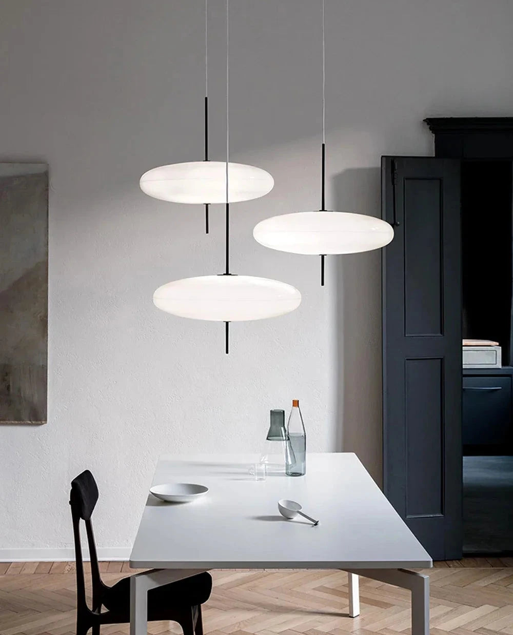 Modern dining room with three pendant Hovering Cloud Pendant lights in white by Domus Collective hanging above a table.