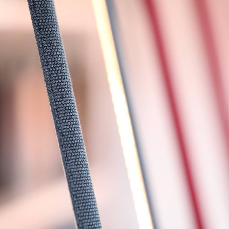Detail view of the Illuminus Threads Suspension Light's woven fabric sleeve in blue beside illuminated white and red options, showcasing the quality textile construction and warm diffused glow, by Domus Collective.