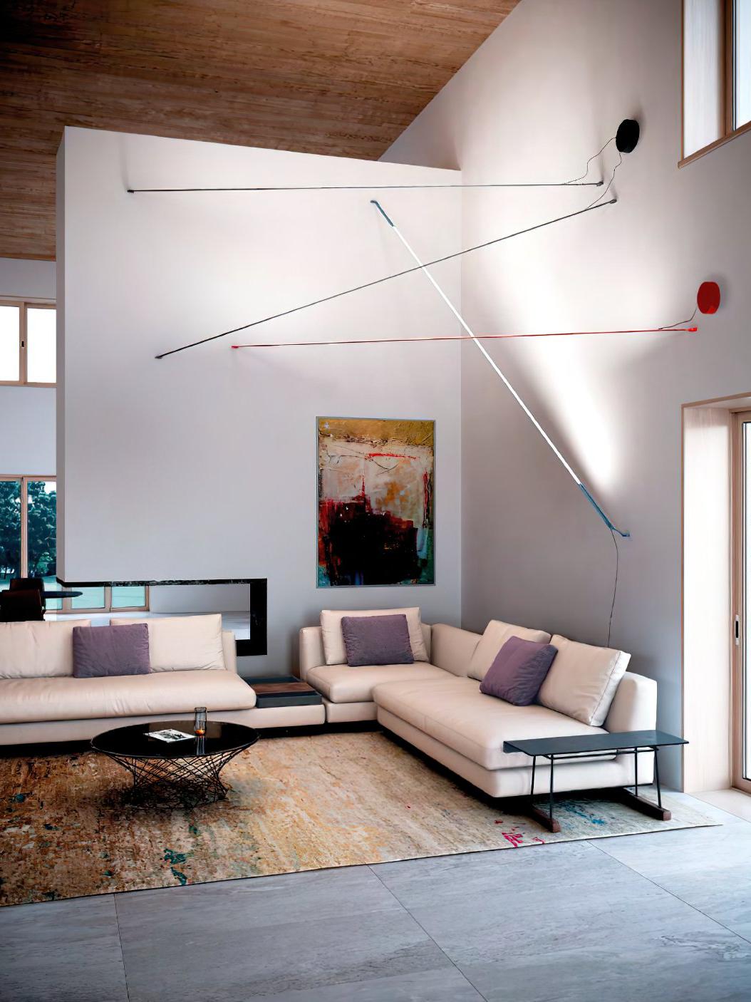 Dynamic installation of Illuminus Threads Suspension Lights in black, white, red, and blue creating intersecting diagonal lines across a double-height living room with contemporary furnishings and abstract art, by Domus Collective.