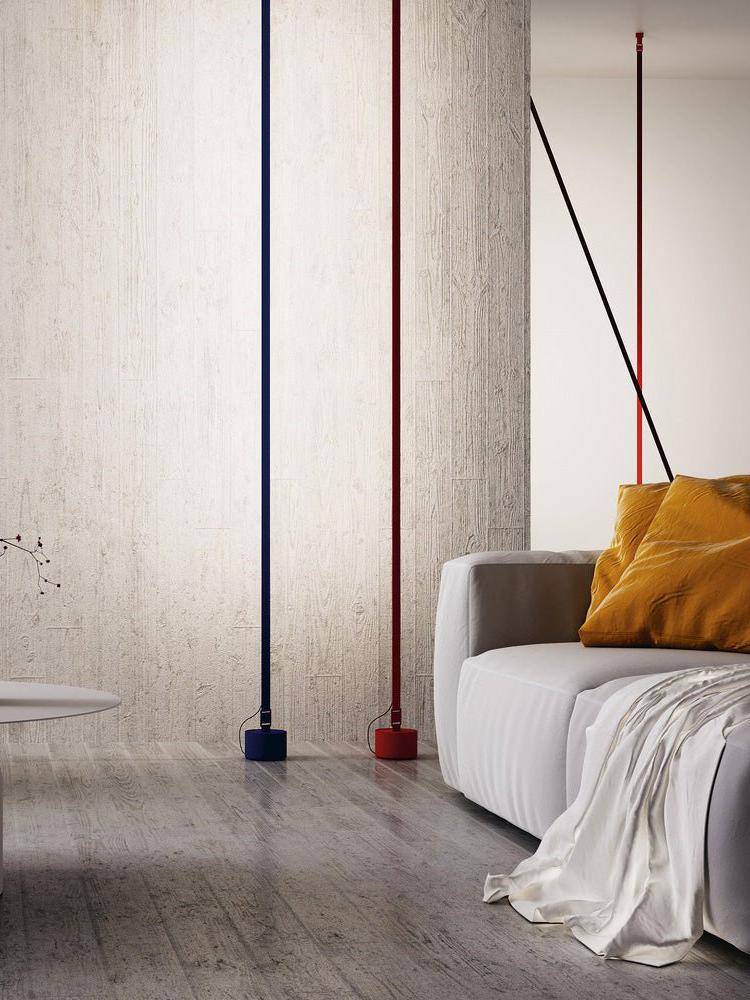 Navy and red Illuminus Threads Suspension Light with matching cylindrical bases creating vertical accents in a minimalist living room with textured walls and modern furniture, by Domus Collective.