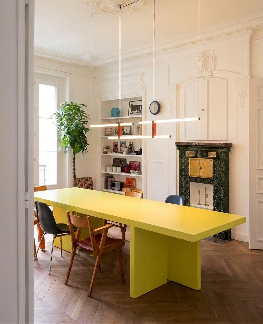 In Parallel Suspension Light in red vegan leather, parallel lines of soft illumination in a characterful heritage room, a timeless contrast with a bold yellow table, by Domus Collective.