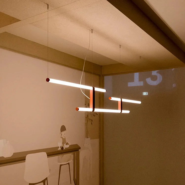 In Parallel Suspension Light in red vegan leather, opal tubes casting a warm ambient glow across a softly lit room, layered lighting with an elevated, calm presence, by Domus Collective.