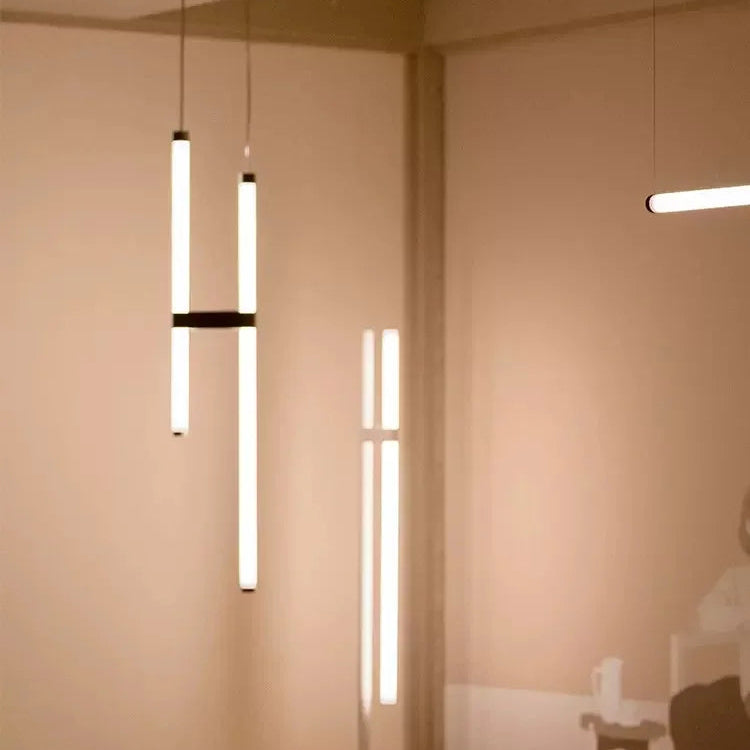 In Parallel Suspension Light in black vegan leather, two tubes hung vertically and joined by a single vegan leather band, a sculptural column of soft illumination, by Domus Collective.