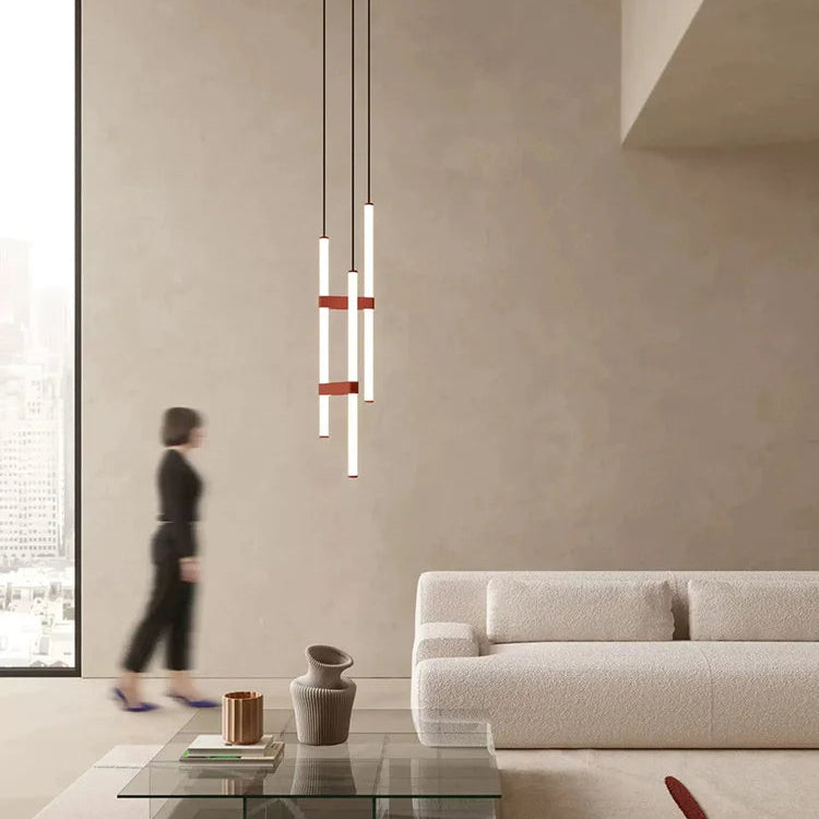 In Parallel Suspension Light in red vegan leather, three vertical lines of light rising above a calm contemporary living room with organic textures and sculptural ceramics, by Domus Collective.