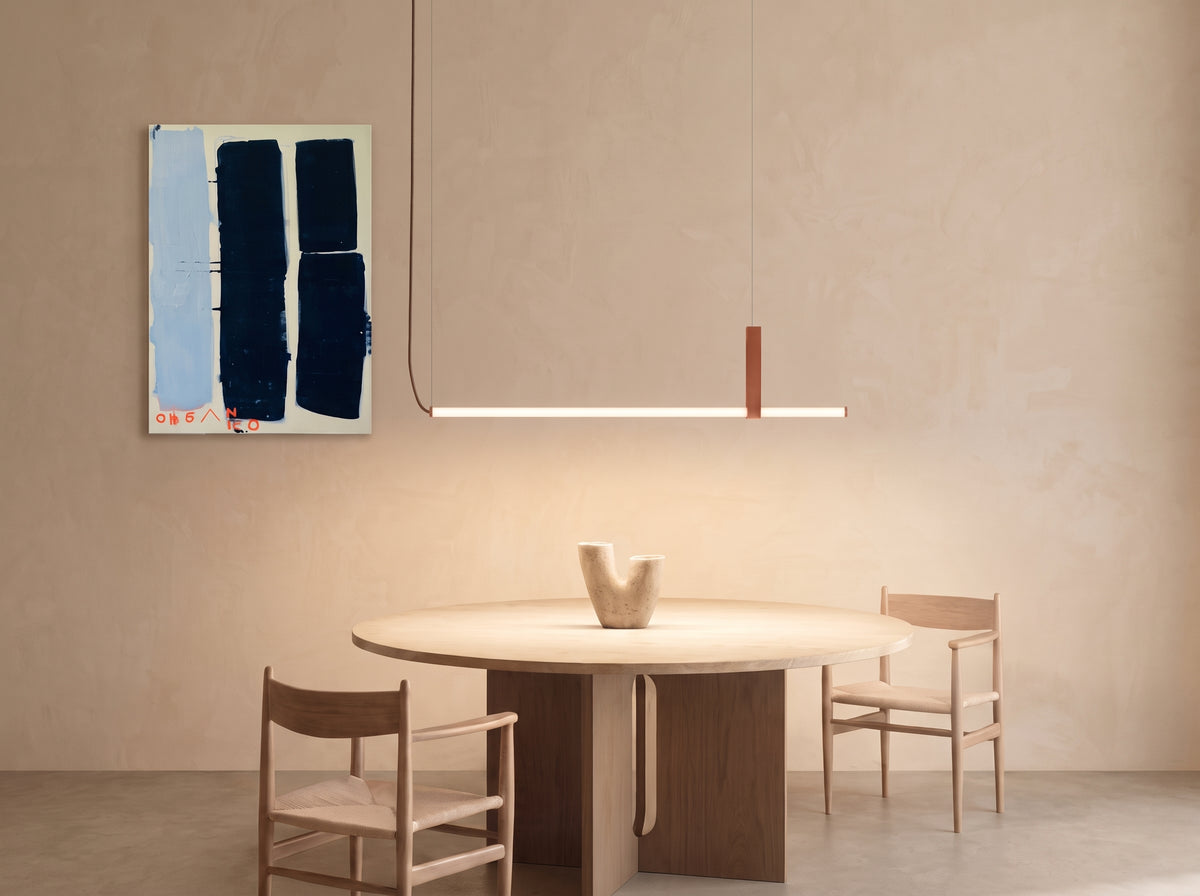 In Parallel Suspension Light in red vegan leather, a minimalist line of opal light held by a soft vegan leather band above a round timber table, organic textures in a calm, contemporary dining space, by Domus Collective.