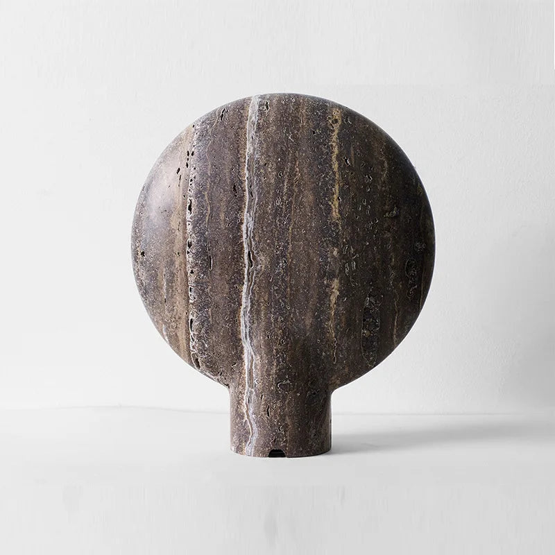 Rear view of the Jupiter Halo Table Lamp showcasing rich dark travertine with distinctive white striations and organic porous surface, solid stone construction with cord channel detail, by Domus Collective.