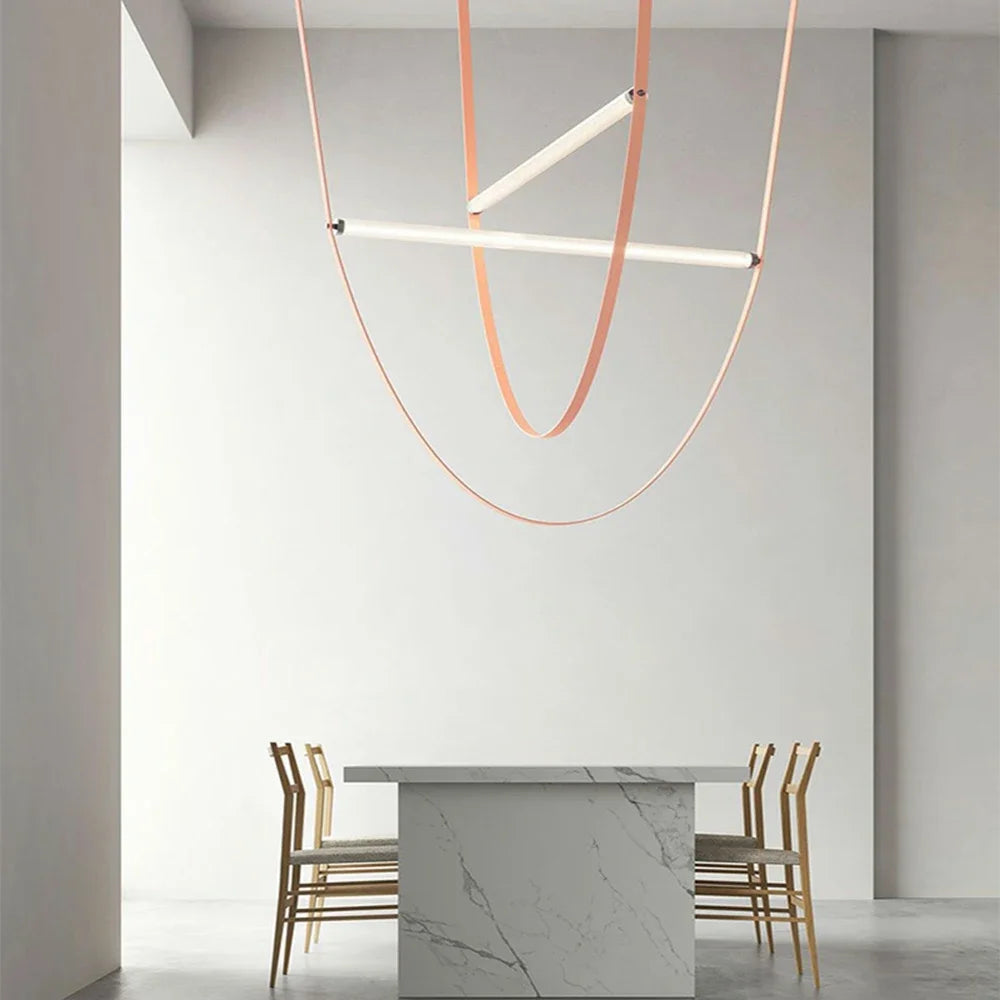 Leather Trapeze Suspension Light with dual peach leather loops suspended above marble dining table, elegant artisan pendant bringing refined warmth to minimalist entertaining spaces, by Domus Collective.