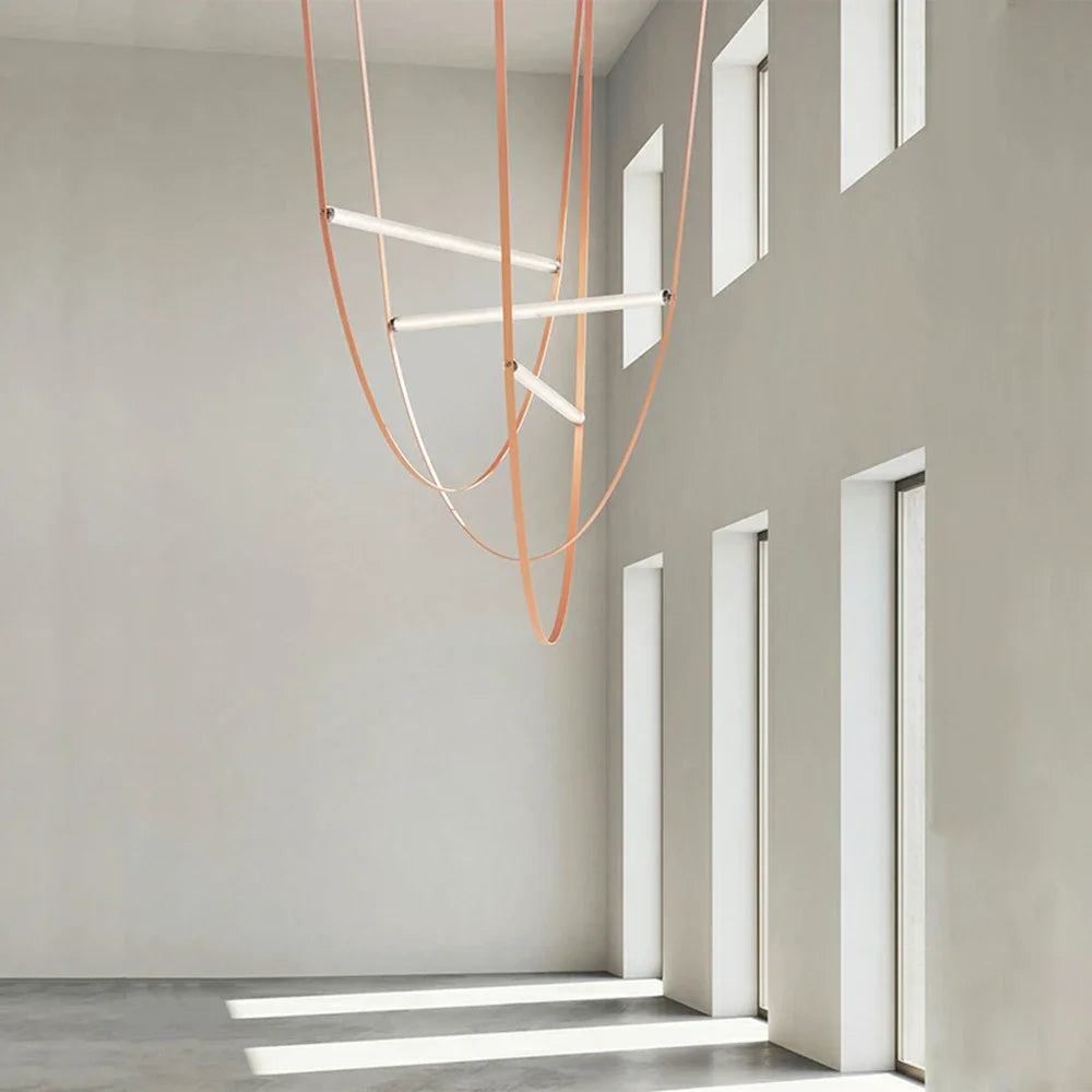 Cascading Leather Trapeze Suspension Lights with peach and coral leather straps in double-height architectural space, artisan lighting installation adding dynamic visual interest to minimalist galleries, by Domus Collective.