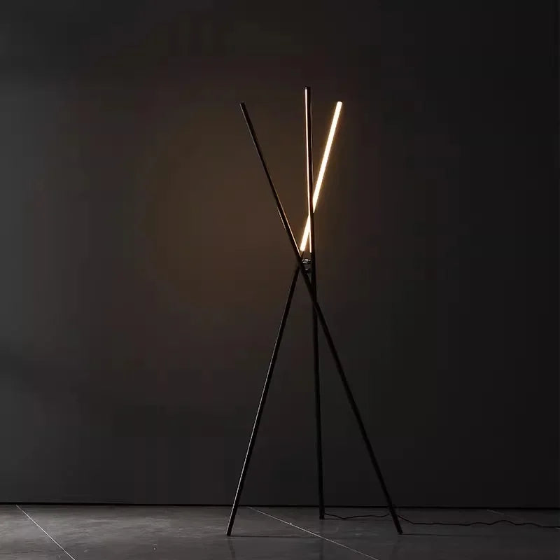 Dramatic Linear Tension Floor Lamp in black finish glowing against a dark backdrop, its striking crossed silhouette and integrated LED lighting embodying controlled sophistication for moody spaces.