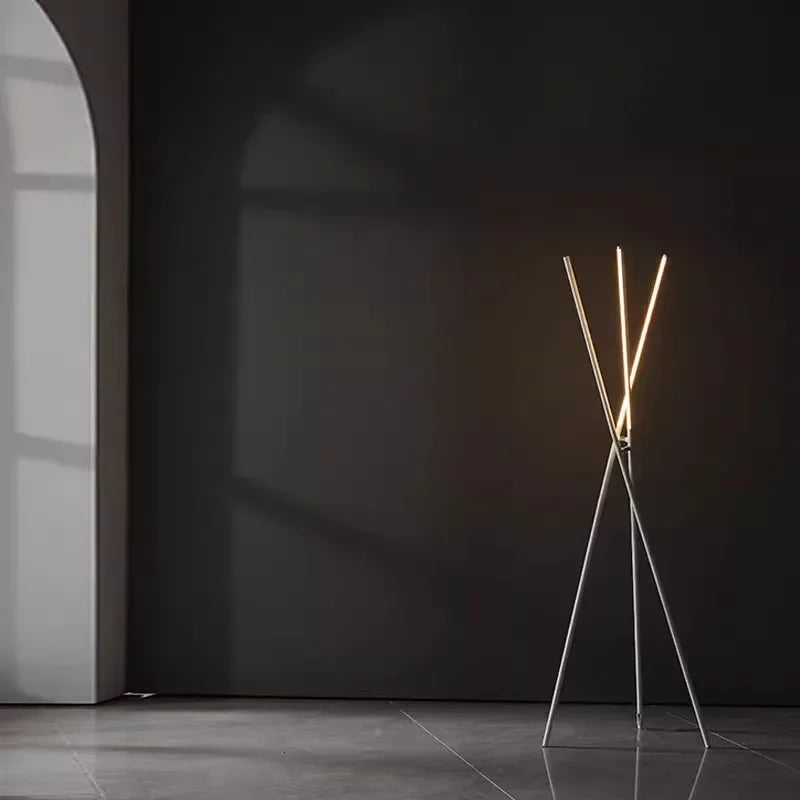 Sculptural Linear Tension Floor Lamp in white metal with tripod stance and dual illuminated bars, casting warm ambient light in a modern architectural setting, by Domus Collective.