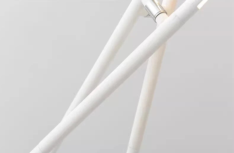 Precision engineering detail of the Linear Tension Floor Lamp showing chrome connector hardware joining sleek white metal tubes, exemplifying the artisan construction behind its sculptural form.