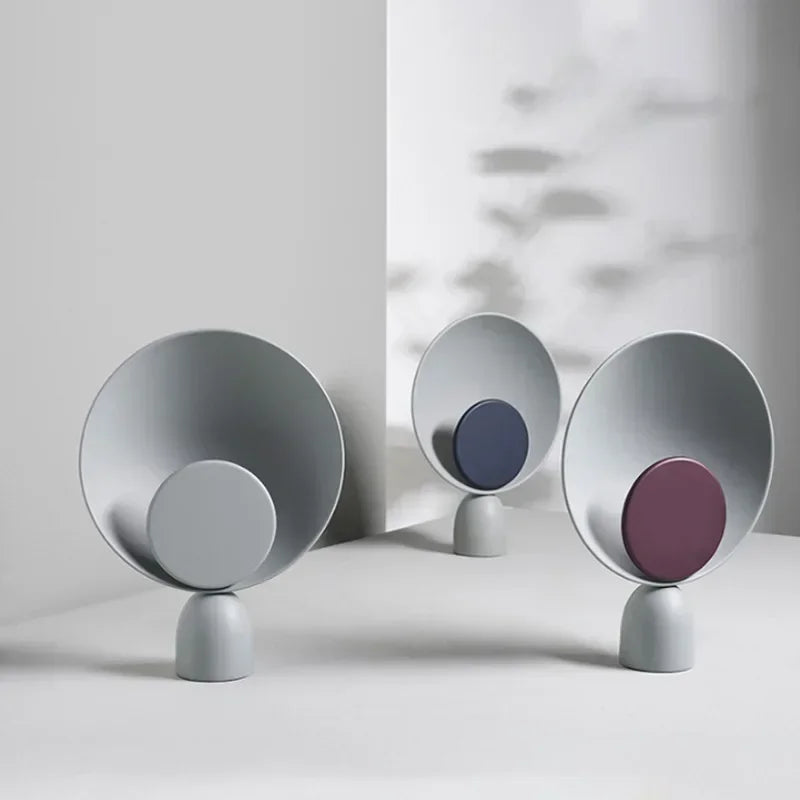 Three Lunar Eclipse Table Lamps in grey, navy, and burgundy accent variations arranged in natural light, showcasing the refined color palette and contemporary artistry of the collection.