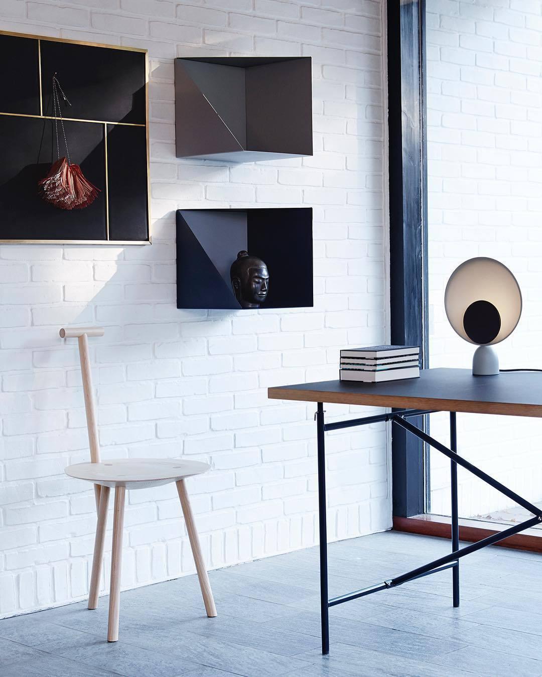 Lunar Eclipse Table Lamp with black accent disc on grey base positioned on a modern desk in a white brick loft, adding sculptural elegance to creative workspaces, by Domus Collective.