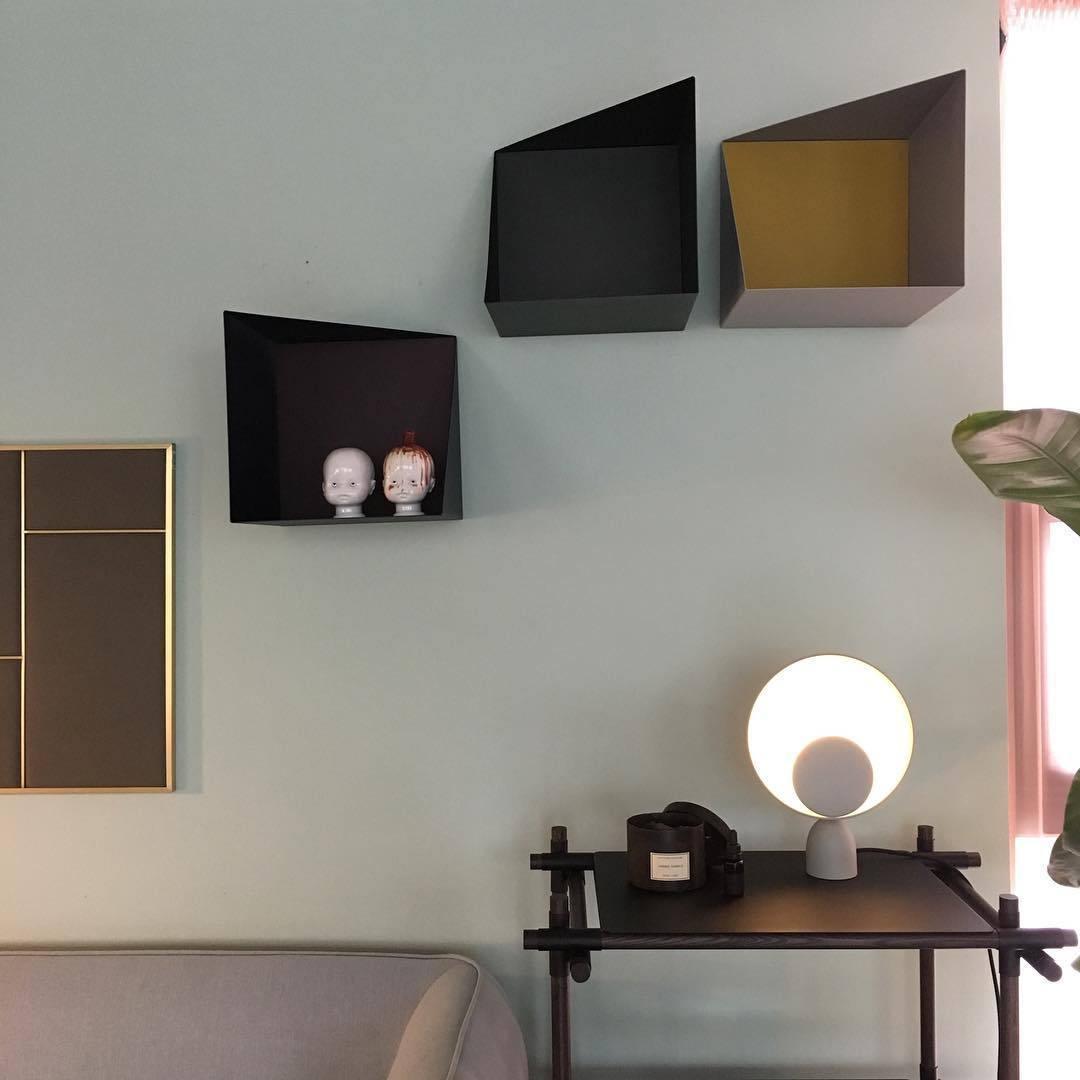 Lunar Eclipse Table Lamp with grey base and black accent disc casting soft ambient glow on a styled side table in a contemporary living space with geometric wall shelving, by Domus Collective.