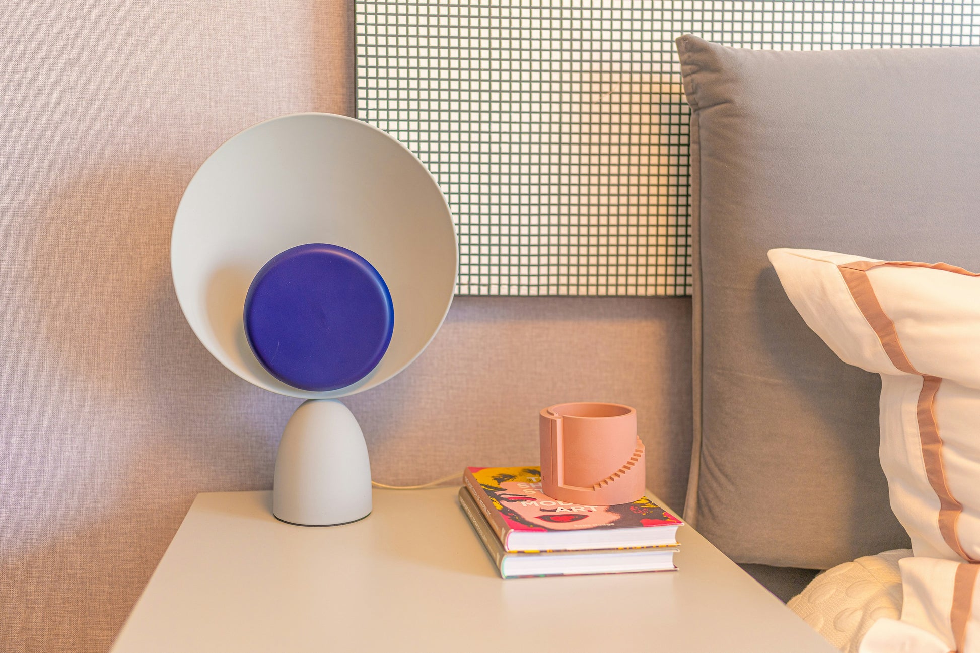 Lunar Eclipse Table Lamp in grey-b with navy blue accent disc positioned on a bedside table, its cosmic form and soft diffused light bringing artistic elegance to contemporary bedroom styling, by Domus Collective.