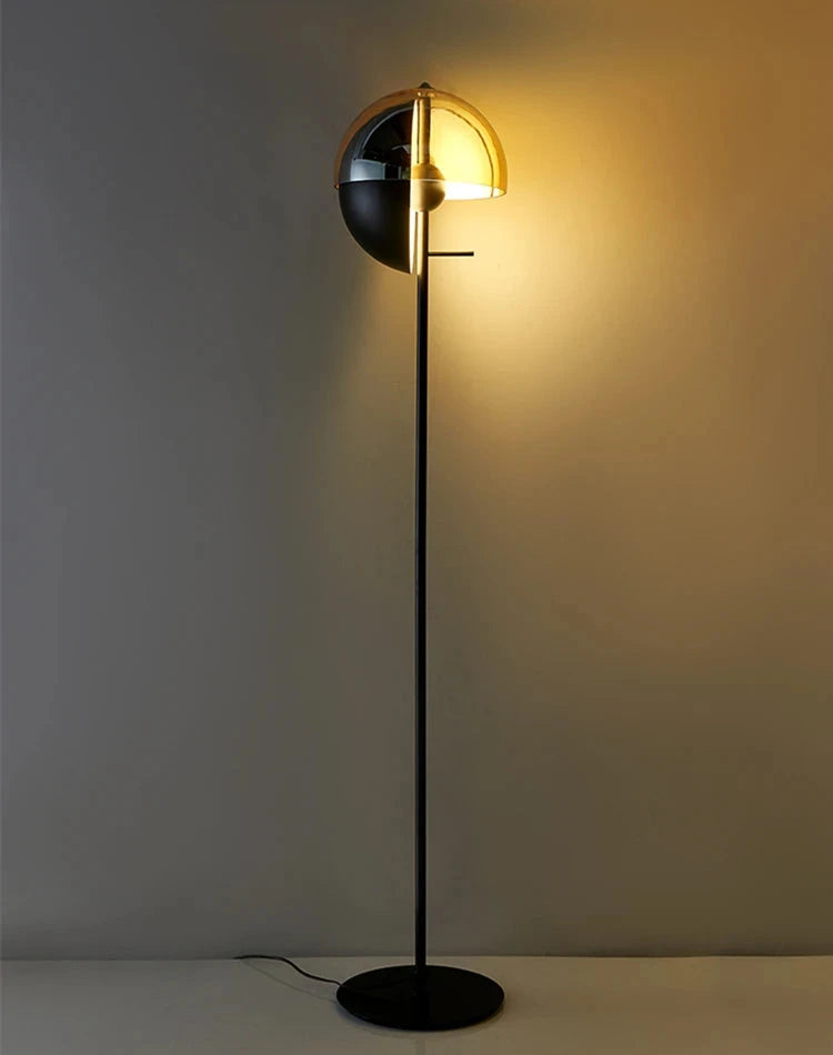 Full-length view of the Lunar Visor Floor Lamp showcasing its spherical split-dome shade with golden glow on slim matte black pedestal, contemporary floor lighting by Domus Collective.